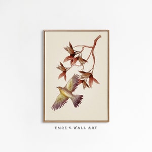 May include: A watercolor painting of a bird in flight with brown and yellow feathers, against a background of a branch with red leaves. The painting is framed in a light wood frame.