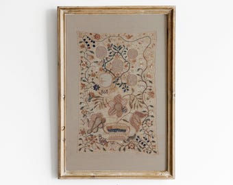 Op de afbeelding: Een ingelijst kunstwerk met een geborduurd ontwerp met bloemen en botanische elementen in tinten beige, bruin en oranje. Het kunstwerk is gevat in een goudkleurige houten lijst. De tekst "EMRE'S WALL ART" is zichtbaar aan de onderkant.