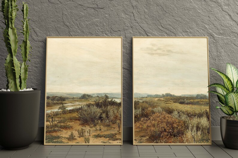 May include: Two framed landscape paintings with a muted color palette depicting a river winding through a field of tall grasses and trees under a cloudy sky.