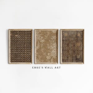 Pode incluir: Três peças de arte de parede emolduradas com padrões de estilo vintage. As molduras são de cor castanho claro. Os padrões incluem um design geométrico castanho escuro, um design floral bege e um design geométrico castanho escuro. O texto "EMRE'S WALL ART" está abaixo.