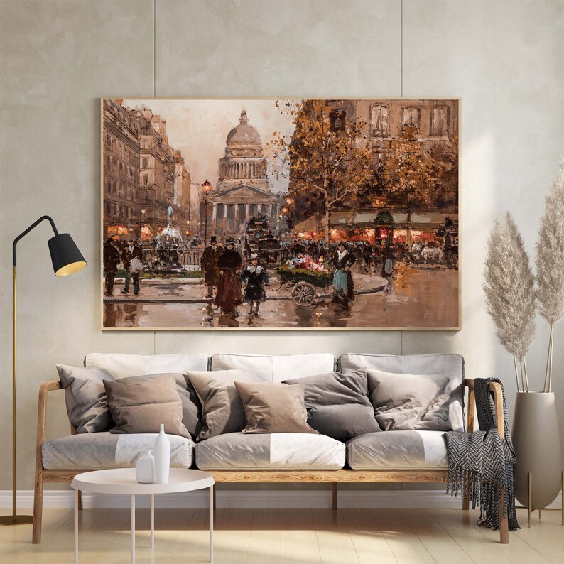May include: A framed oil painting depicts a bustling Parisian street scene. The artwork features a large domed building, figures, and a flower cart. The color palette is dominated by warm browns, tans, and touches of blue, creating a vintage aesthetic.