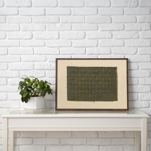 Digital print of a green textile pattern with gold geometric motifs, antique fabric wall art reproduction, textured tapestry design in muted tones.