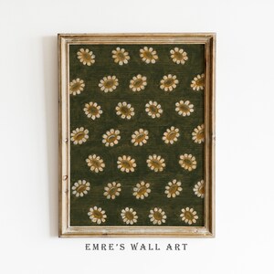May include: A framed wall art print featuring a dark olive green background with a repeating pattern of small, stylized white and yellow daisy flowers. The artwork is enclosed in a light-colored wooden frame with a visible grain texture.
