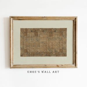May include: A framed artwork featuring a rectangular textile with a patchwork design in shades of brown and beige. The textile has floral patterns and is set against a light green background. The frame is a distressed gold color, and the text "EMRE'S WALL ART" is at the bottom.