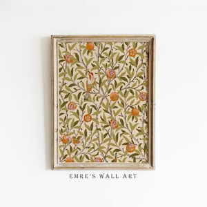 May include: A framed print of a vintage botanical illustration featuring a repeating pattern of green leaves, orange pomegranates, and small birds. The print has a cream background and is framed in a light wood frame.