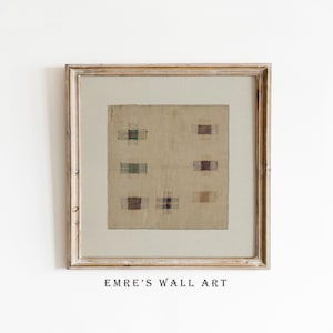 Könnte beinhalten: Gerahmtes Kunstwerk mit einem beigefarbenen Textil mit sechs rechteckigen Flecken in Braun-, Grün- und Blautönen. Das Kunstwerk ist in einem hellen Holzrahmen gefasst. Der Text "EMRE'S WALL ART" befindet sich unten.
