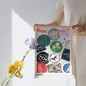 May include: A framed print with a collage of colorful circular stickers featuring various business names and logos, including "alula's", "Cardinal Provisions", "PYC Surf Bar", "The Stone Pony", "Asbury Park", "Black Swan", "Lola", "Homesick", "The Robins Ale House", and "Wonder Bar".