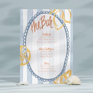 May include: A blue and white striped sign with a hand-drawn lemon design and the text "The Bar" in orange. The sign lists cocktails, beer and seltzers, and wine options.