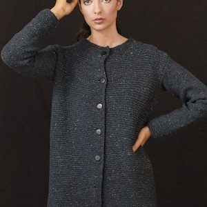 Può includere: Un cardigan grigio scuro con bottoni. Il cardigan è realizzato in tessuto a maglia testurizzato.