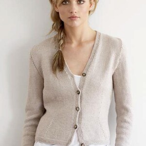 May include: A light beige cardigan with a v-neck and button closure. The cardigan is made of a soft, knitted fabric and has long sleeves.