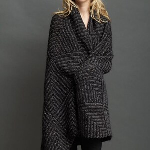 May include: A black and grey geometric patterned knitted cardigan with a shawl collar.