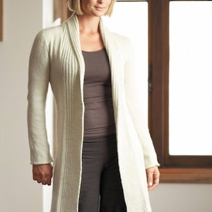 以下が含まれることがあります： 幅広の襟とリブ編みのテクスチャを持つ、長い白いカーディガン。カーディガンは前面が開いており、長袖です。