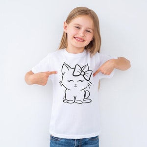 Könnte beinhalten: Weißes T-Shirt mit einer schwarzen Linienzeichnung einer Katze, die eine Schleife trägt. Die Katze sitzt mit ihren Pfoten zusammen und hat die Augen geschlossen.