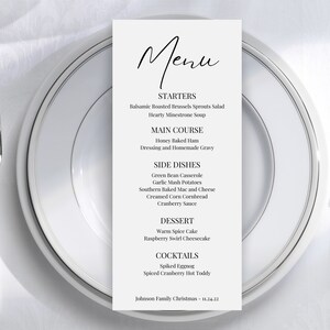 May include: A black and white menu for a Christmas dinner. The menu includes starters, main course, side dishes, dessert, and cocktails. The menu lists Balsamic Roasted Brussels Sprouts Salad, Honey Baked Ham, Green Bean Casserole, Warm Spice Cake, Spiked Eggnog, and Spiced Cranberry Hot Toddy.