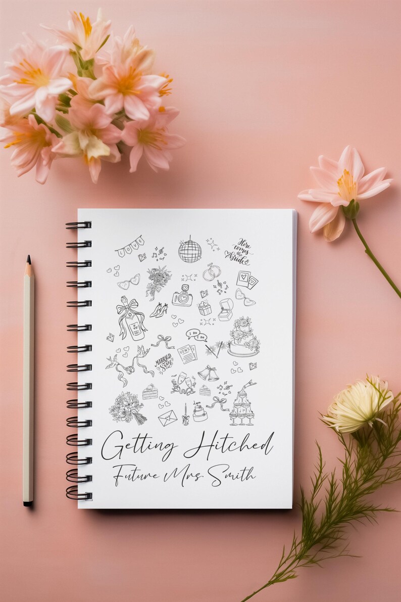 May include: A white spiral-bound notebook with black line art illustrations of wedding-related icons, including a cake, rings, and flowers. The text "Getting Hitched Future Mrs. Smith" is written below the illustrations. A pencil and pink flowers are also in the image.