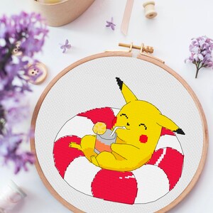 May include: A yellow Pikachu character with red cheeks is sitting in a red and white inflatable ring, holding a yellow and orange drink with a straw. The character is smiling and has a black tail.