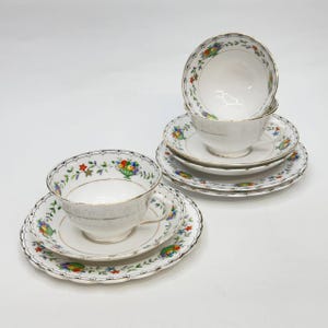 Könnte beinhalten: Ein Set aus Vintage-Teetassen und Untertassen. Die weißen Porzellantassen und Untertassen weisen ein Blumendesign mit Goldrand auf. Das Set enthält zwei Tassen und Untertassen sowie zwei zusätzliche Untertassen.