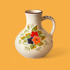 May include: Cream ceramic jug with a handle and a floral pattern. The flowers are red, orange, and purple, with green leaves and small red accents. The rim and handle are brown.