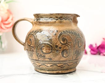 Jarra de cerámica vintage firmada por Studio Pottery, con esmalte marrón con motivos vegetales.