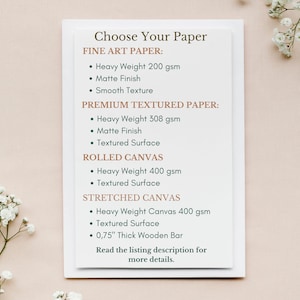 May include: A white card with the text "Choose Your Paper" in brown text. The card lists different paper and canvas options for prints, including fine art paper, premium textured paper, rolled canvas, and stretched canvas. Each option lists the weight of the paper or canvas in grams per square meter (gsm) and the surface texture.
