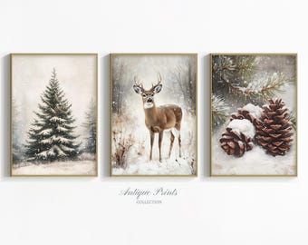 May include: Set of three framed winter art prints. The prints feature a snowy evergreen tree, a deer in a snowy forest, and snow-covered pine cones with evergreen branches. The prints have a vintage aesthetic with a gold frame.