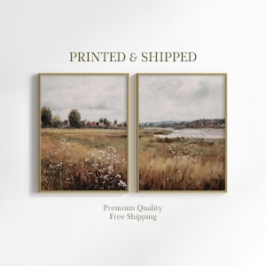 May include: Two rectangular wall art prints in thin gold frames featuring landscape paintings of a rural field with tall grasses, wildflowers, and distant houses under a cloudy sky. The text PRINTED & SHIPPED and Premium Quality Free Shipping appears.