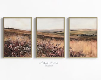 May include: Set of three framed landscape prints. Each print features a field of tall grass and wildflowers in shades of brown, pink, and white, with rolling hills in the background. The frames are gold-colored.