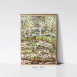 May include: A framed painting of a white bridge over a pond with water lilies. The bridge is painted in a light blue color and the water lilies are painted in shades of green, white, and pink. The painting is set against a background of trees and foliage.