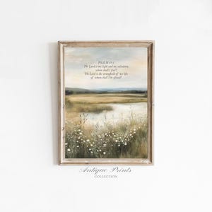 May include: A framed art print depicting a tranquil landscape with a field, water, and text from Psalm 27:1. The artwork has a vintage style with muted colours and a rustic wooden frame. The words "Antique Prints Collection" are at the bottom.