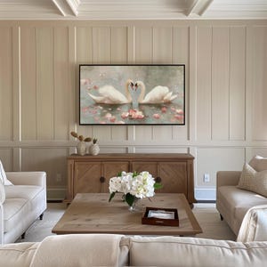 May include: A living room scene featuring a framed artwork of two swans forming a heart shape. The artwork hangs above a wooden cabinet. A coffee table with a floral arrangement and two sofas complete the room's decor.
