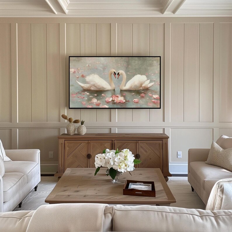 May include: A living room scene featuring a framed artwork of two swans forming a heart shape. The artwork hangs above a wooden cabinet. A coffee table with a floral arrangement and two sofas complete the room's decor.