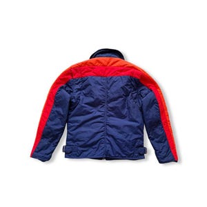 May include: A blue, red, and orange jacket. The jacket has a blue body with red stripes down the sleeves and across the shoulders. The collar is orange. The jacket has two small buckles at the waist.