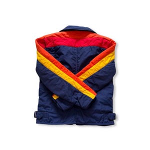 May include: A vintage blue jacket with red and orange accents on the shoulders and collar. The sleeves feature yellow and orange stripes. The jacket has a collared neckline and two adjustable waist straps.