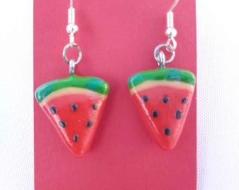 May include: A pair of watermelon slice earrings with silver hooks. The earrings are made of red, green, and black polymer clay.