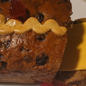 May include: A sliced loaf of raisin bread with a brown icing swirl on top and a slice of cheddar cheese inside.