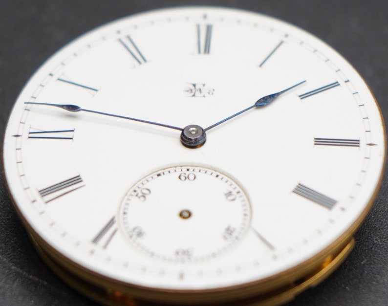 May include: A white pocket watch with Roman numeral hour markers and a smaller subdial. The watch hands are blue steel.