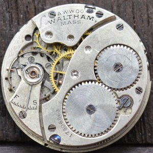 May include: Close-up of a silver pocket watch movement with the inscription "A.W.W.CO. WALTHAM, MASS." and the serial number "1780890".