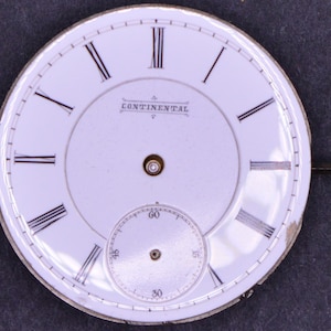 May include: White watch face with black Roman numeral hour markers and black minute markers. The watch face has the word "CONTINENTAL" printed in black.