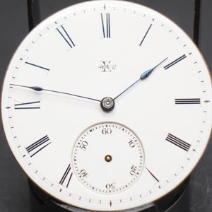 May include: A white pocket watch face with black Roman numeral hour markers and black minute markers. The watch has a small, white sub-dial with black numbers for seconds. The watch face has a blue steel hand for the seconds and a black steel hand for the minutes. The watch face has the letter "E" with a number "3" above it.