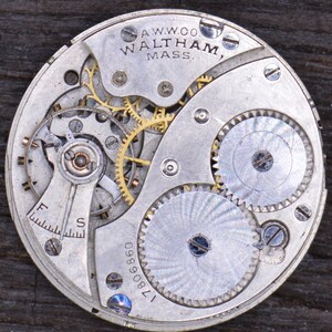 May include: Close-up of a silver watch movement with gold gears. The movement is labeled "A.W.W.Co. Waltham, Mass." and "17809890".