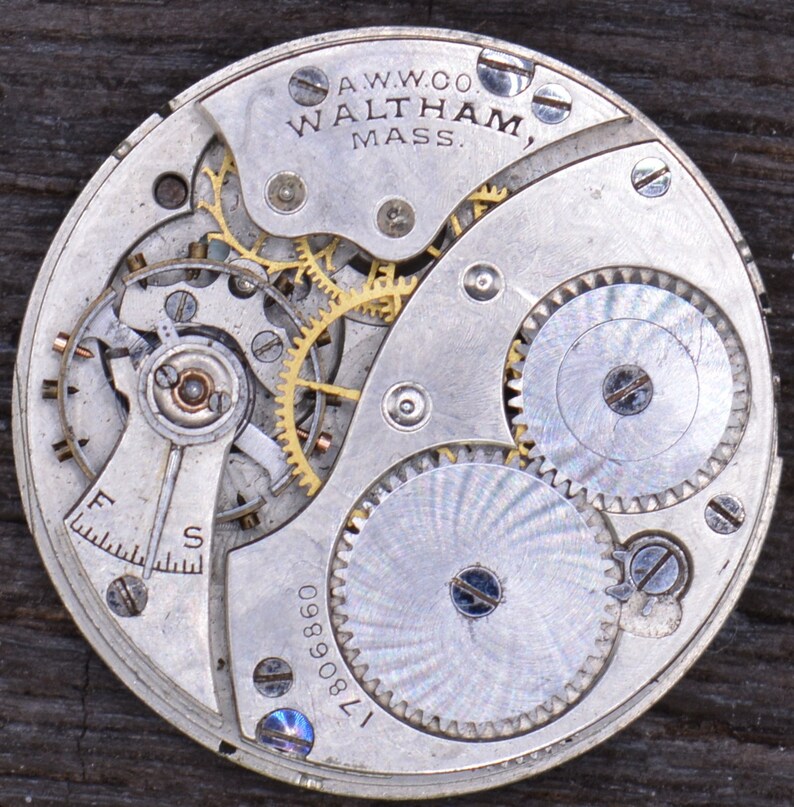 May include: Close-up of a silver watch movement with gold gears. The movement is labeled "A.W.W.Co. Waltham, Mass." and "17809890".