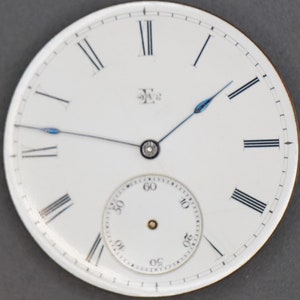 May include: White pocket watch face with black Roman numeral hour markers and black minute markers. The watch has a smaller white sub-dial with black minute markers and black numbers for the seconds. The watch hands are black with blue tips.