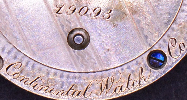 May include: Close-up of a silver watch back with the inscription "Continental Watch Co." and the number "19093".