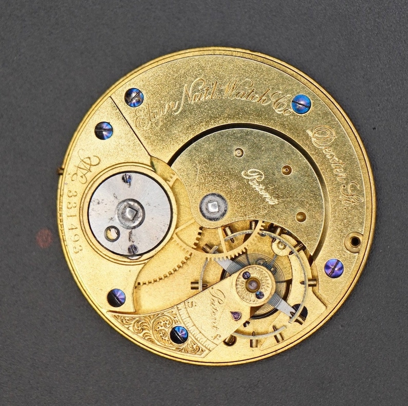 May include: A gold pocket watch with intricate gears and a detailed inscription that reads "E. Howard Watch Co. Boston, Mass. Patent No. 331493".