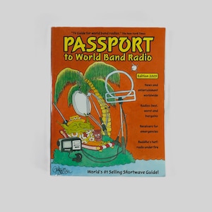 May include: A colorful book cover with the title "PASSPORT to World Band Radio" and the subtitle "World's #1 Selling Shortwave Guide!" The cover features a cartoon illustration of a person listening to a radio under a palm tree.