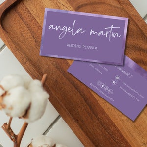 May include: Purple business card with a watercolour background and the text "angela martin" in white script font. The text "wedding planner" is also in white font. The back of the card has contact information and social media handles.