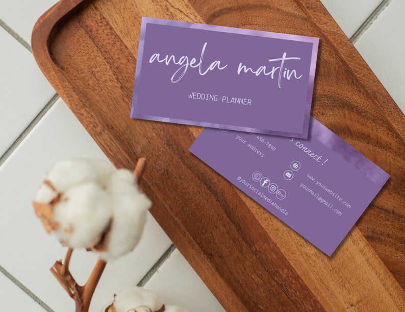 May include: Purple business card with a watercolour background and the text "angela martin" in white script font. The text "wedding planner" is also in white font. The back of the card has contact information and social media handles.
