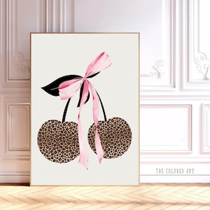 Puede incluir: Dos cerezas rosas y marrones con un lazo rosa en la parte superior. Las cerezas tienen un estampado de leopardo. El texto "THE COLORED JOY" está en la parte inferior de la imagen.