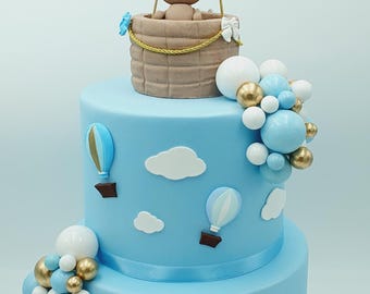 A spectacular birth/christening cake made of EVA foam with cold porcelain, paper, and bauble decorations. A teddy bear in a hot air balloon theme.