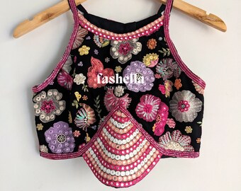 May include: A black halter top with a floral design and sequins. The top has a scalloped hemline and is decorated with pink, purple, and orange flowers. The text "fashella INDIAN WEAR" is visible on the front of the top.
